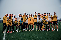 Der Profikader von Dynamo Dresden hält ein signiertes Heimtrikot in die Kamera
