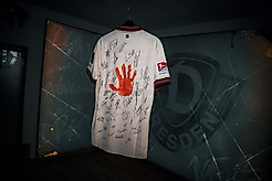 Das sandsteinfarbene Trikot der SGD mit einem orangenen Handabdruck und den Unterschriften des Zweitligateams sowie der Frauenmannschaft.