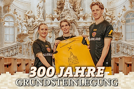 Drei Personen präsentieren in einer Kirche ein Fußballtrikot - darunter der Text 300 Jahre Grundsteinlegung