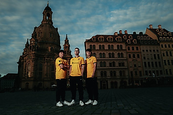 Drei Männer im Dynamo Trikot vor der Dresdner Frauenkirche in der Abenddämmerung