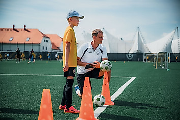 Ein Junge mit einem Trainer auf dem Fußballplatz
