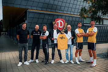 Dynamos Geschäftsführer David Fischer, Cheftrainer Thomas Stamm und die SGD-Spieler Lars Bünning und Stefan Kutschke posieren mit den neuen Teampartnern der Profis vor dem Dynamo-Wappen am Funktionsgebäude im Trainingszentrum der SGD.