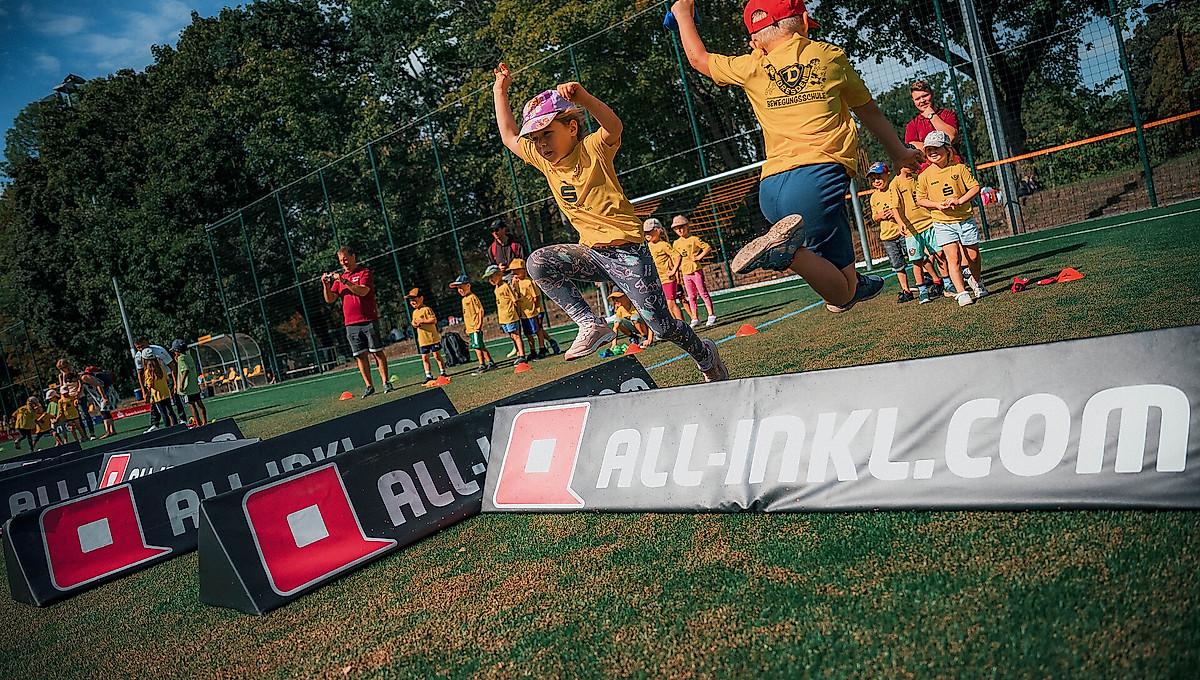 Kinder springen über ein Hindernis.