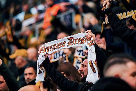 Ein Dynamo-Fan hält im RUdolf-Harbig-Stadion seinen Schal in die Höhe.