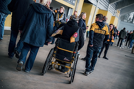 Ein Fan im Rollstuhl umringt von anderen Fans im Rudolf-Harbig-Stadion