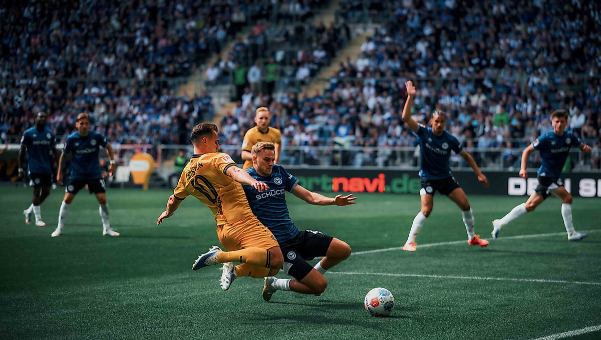 Zwei Spieler grätschen zum Ball.