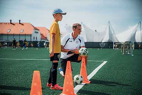 Ein Junge mit einem Trainer auf dem Fußballplatz