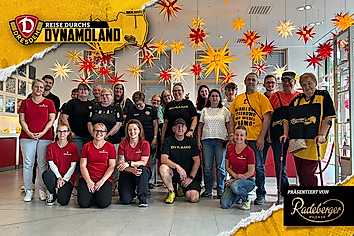 Eine Gruppe Menschen unter zahlreichen bunten Weihnachtssternen.