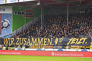 "Wir. Zusammen. Jetzt." signalisieren die rund 1.500 Dynamo-Fans, die den Weg nach Heidenheim angetreten haben. 