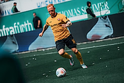 Dynamos Mittelfeldspieler Nils Fröling im gelben Heimtrikot als er eine Flanke beim Auswärtsspiel in Fürth schlägt.