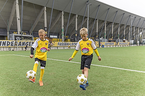 Zwei Jungs halten mit dem Fuß einen Ball hoch