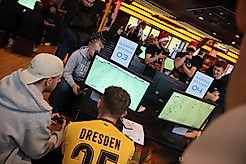 Teilnehmer, die beim Turnier vor der Konsole sitzen und EA FC spielen.