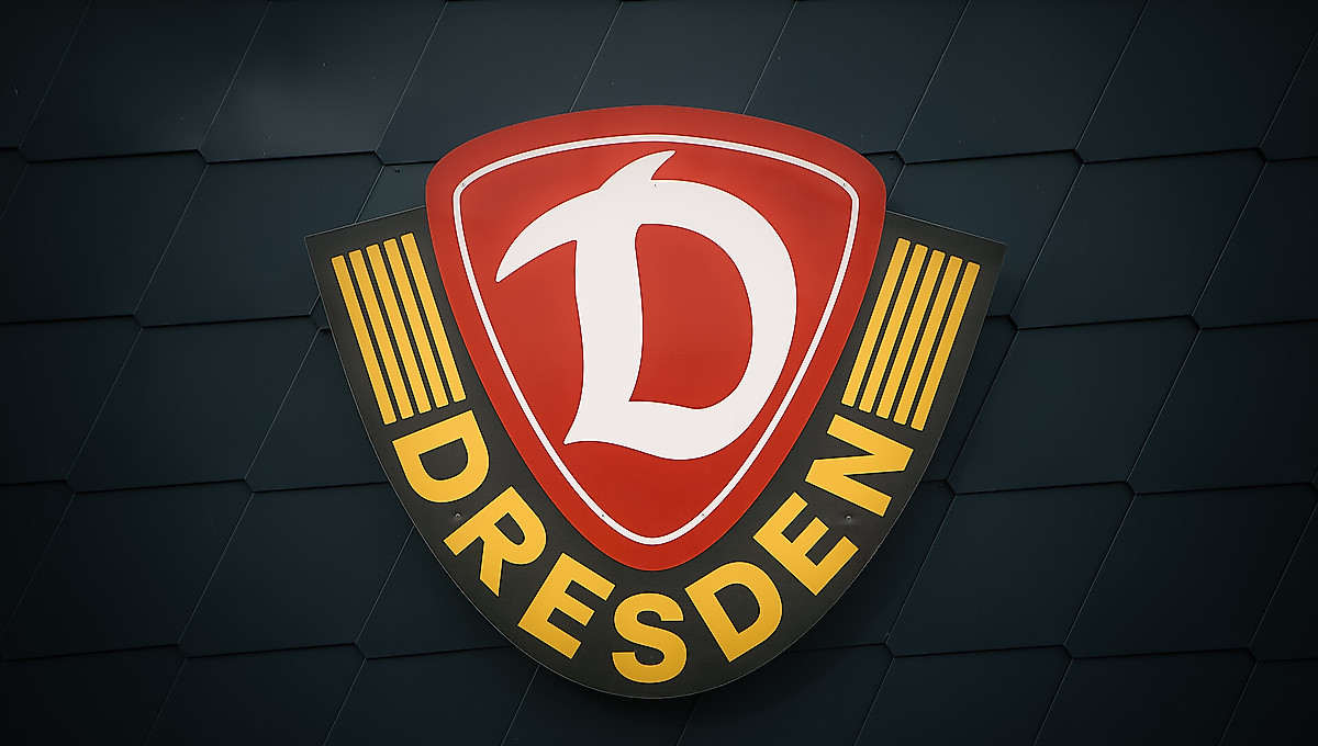 Das Wappen der SG Dynamo Dresden fotografiert auf dunkelgrauen Hintergrund