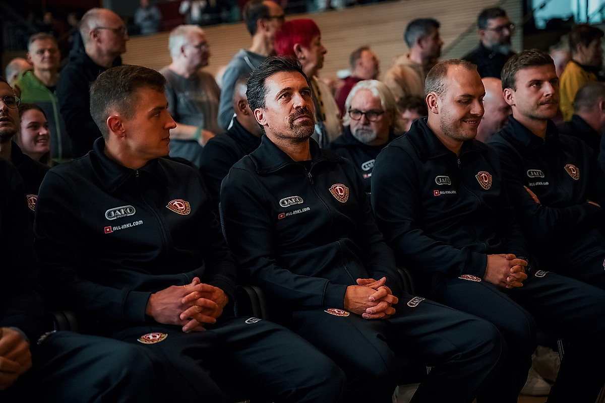 Spieler und Trainer sitzen auf Stühlen und hören der Mitgliederversammlung zu