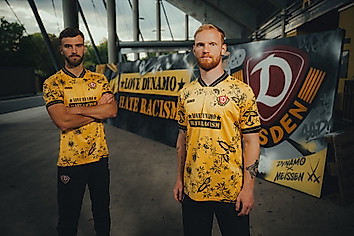 Lars Bünning und Nils Fröling im "Love Dynamo - Hate Racism"-Sondertrikot vor einer Graffitiwand im Stadion.