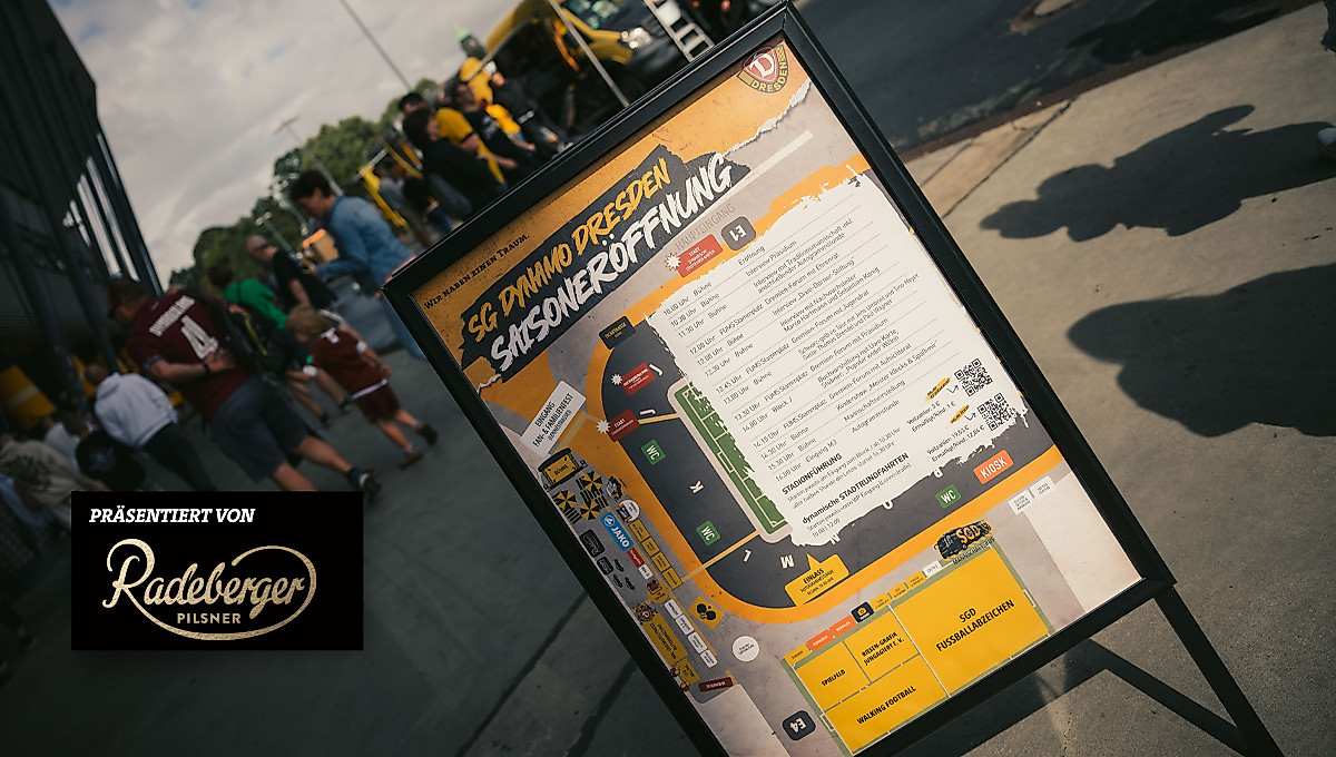 Ein Aufsteller mit dem Programm zur Saisoneröffnung. Im Hintergrund Stadion und Fans.