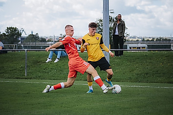 Ein Dynamo-Spieler dribbelt mit dem Ball an einem grätschenden Gegenspieler vorbei.