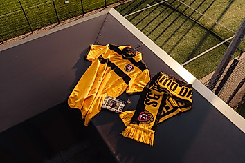 Ein Trikot, ein Schal und eine Postkarte aus der schwarzen Retrobox.