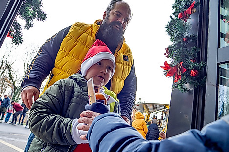 Ein Kind erhält einen vom Dynamo-Nikolaus befüllten Stiefel, dahinter steht sein Vater.