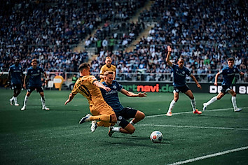 Zwei Spieler grätschen zum Ball.