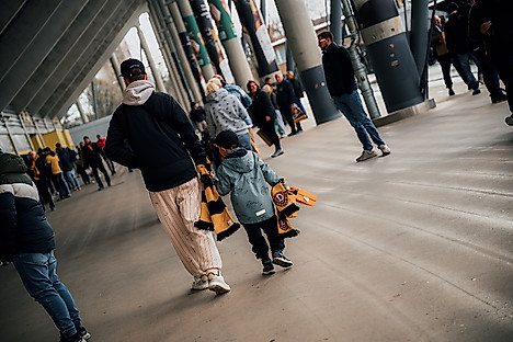 Ein Vater und ein Kind im Stadion, von hinten fotografiert.