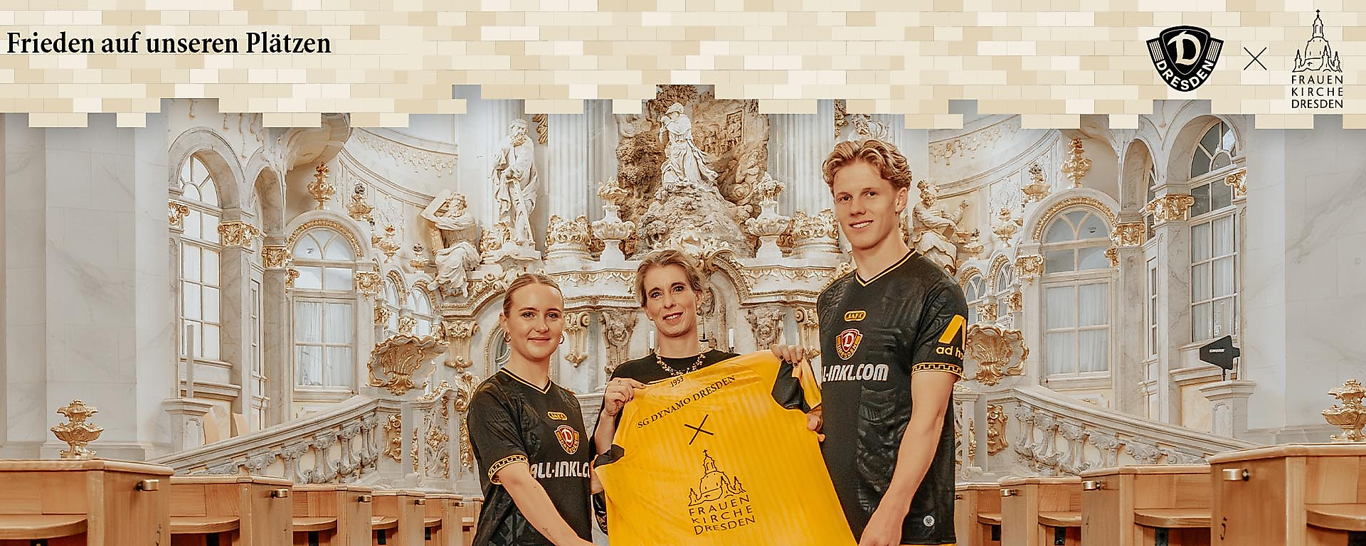 Drei Personen präsentieren in der Dresdner Frauenkirche ein Trikot der SG Dynamo Dresden