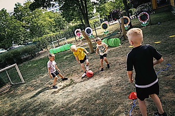Kinder spielen auf einem Spielplatz mit einem Ball.