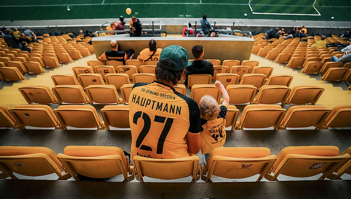 Ein Mann sitzt mit seinem Kind auf der Tribüne des Rudolf-Harbig-Stadions.