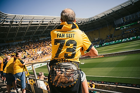 Ein Dynamo-Fan im Rudolf-Harbig-Stadion mit Blick auf das Spielfeld.