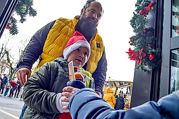 Ein Kind erhält einen vom Dynamo-Nikolaus befüllten Stiefel, dahinter steht sein Vater.