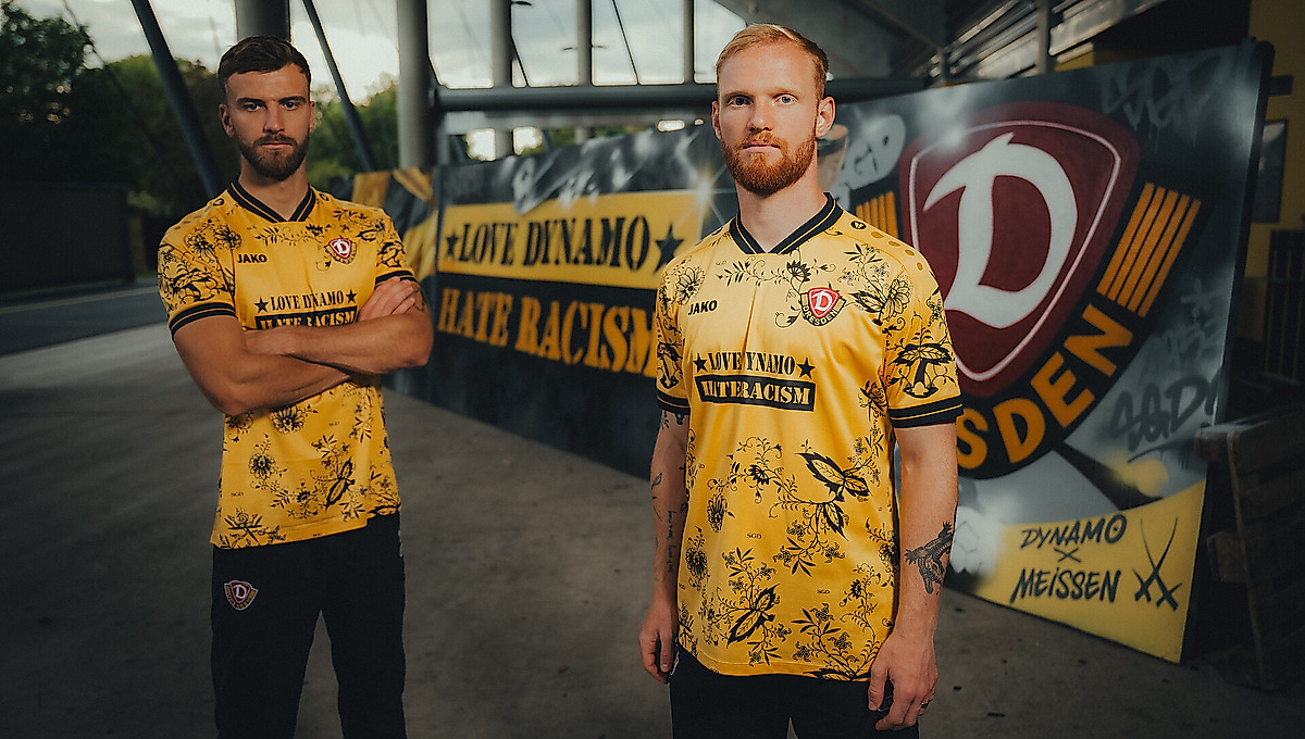 Lars Bünning und Nils Fröling im "Love Dynamo - Hate Racism"-Sondertrikot vor einer Graffitiwand im Stadion.