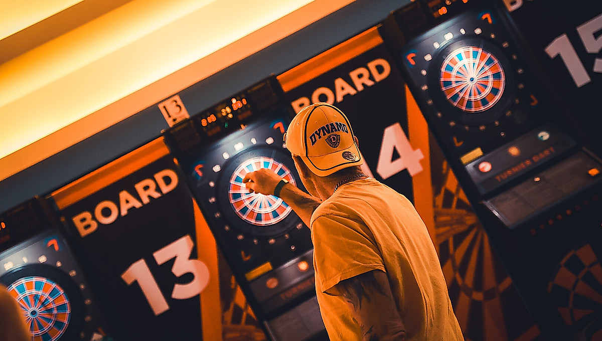 Ein Dynamo-Fan wirft einen Pfeil auf eine Dartscheibe.