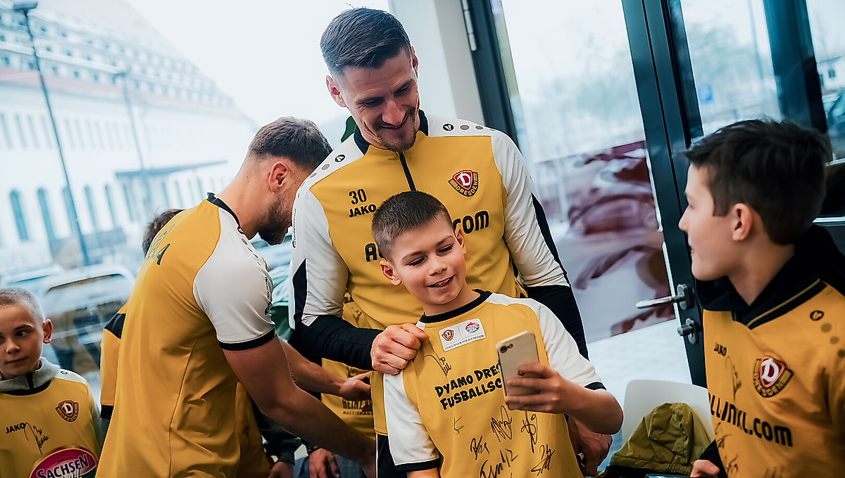 Ein Kinde macht ein Selfie mit Dynamo-Kapitän Stefan Kutschke
