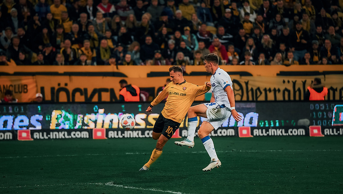 Jakob Lemmer im Zweikampf mit einem Karlsruher Gegenspieler. Lemmer holt zum Schuss aus, der Ball ist vor ihm in der Luft