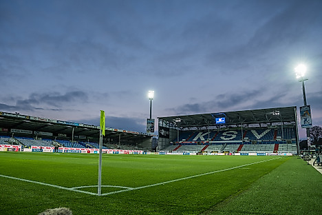 Das leere Kieler Holstein-Stadion bei eingeschaltetem Flutlicht.