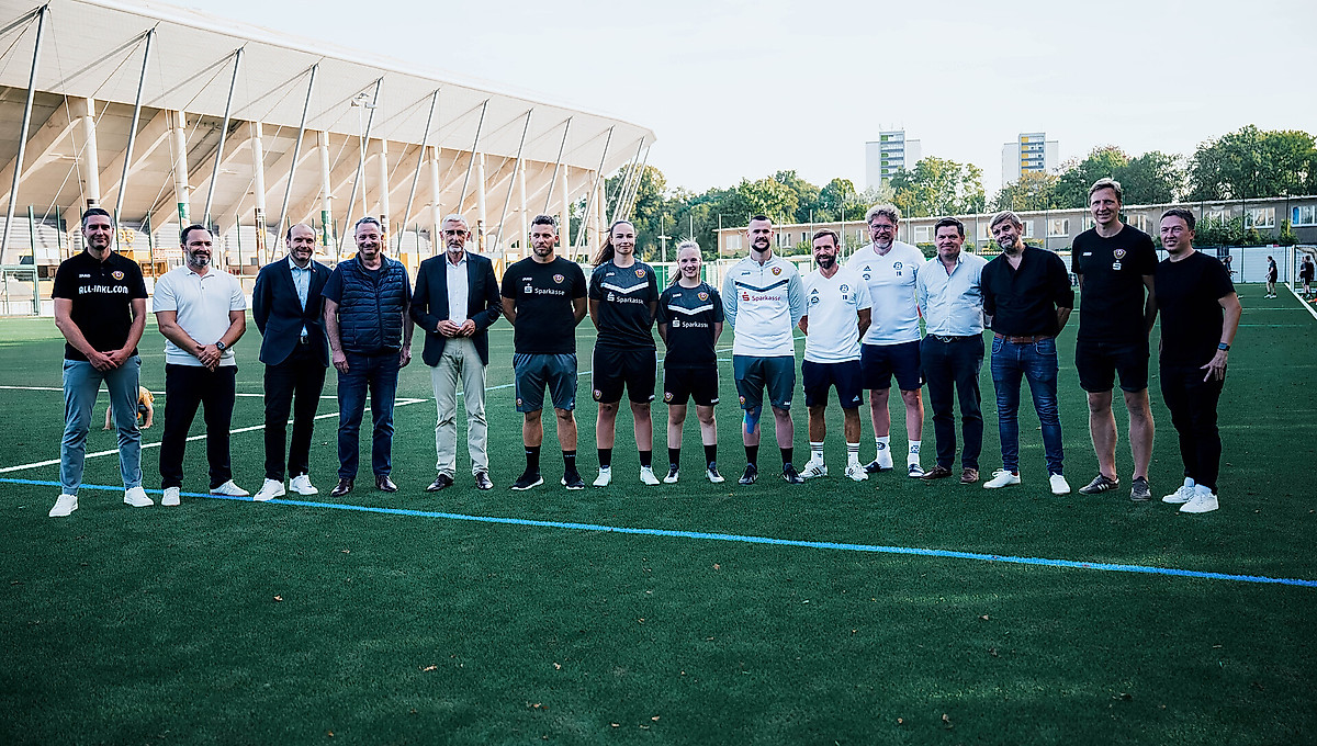 Die Geschäftsführung der SGD steht zusammen mit Vertretern aller beteiligter Vereine und dem geladenen Sächsischen Innenminister Armin Schuster und Sportbürgermeister Jan Donhauser auf dem neuen Kunstrasenplatz am Rudolf-Harbig-Stadion.