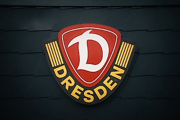 Das Wappen der SG Dynamo Dresden fotografiert auf dunkelgrauen Hintergrund