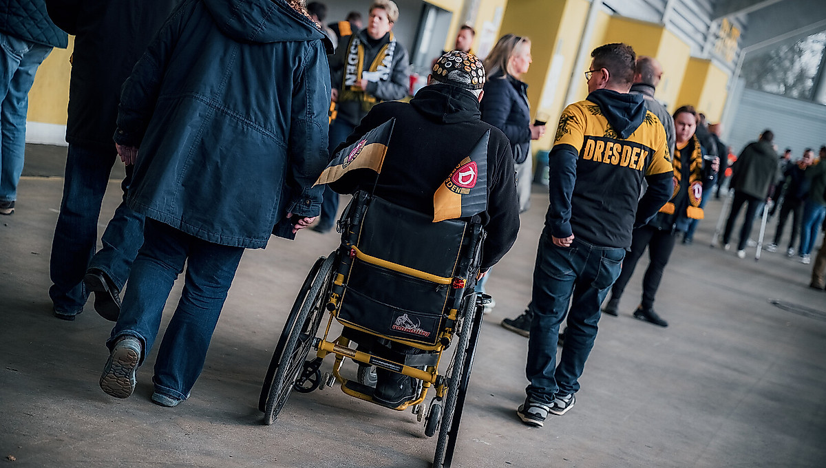 Ein Fan im Rollstuhl umringt von anderen Fans im Rudolf-Harbig-Stadion