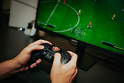 Playstation-Controller mit Dynamo-Wappen vor einem TV-Bildschirm