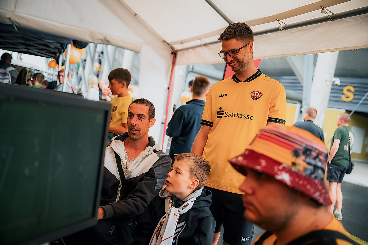 Ein Kind an einer Spielekonsole. Marcel Gramann schaut ihm über die Schulter.