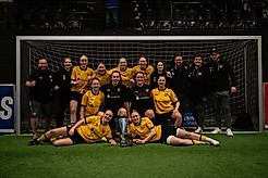 Das Team der Dynamo-Frauen zum Gruppenfoto mit Pokal in einem Fußball-Hallentor.