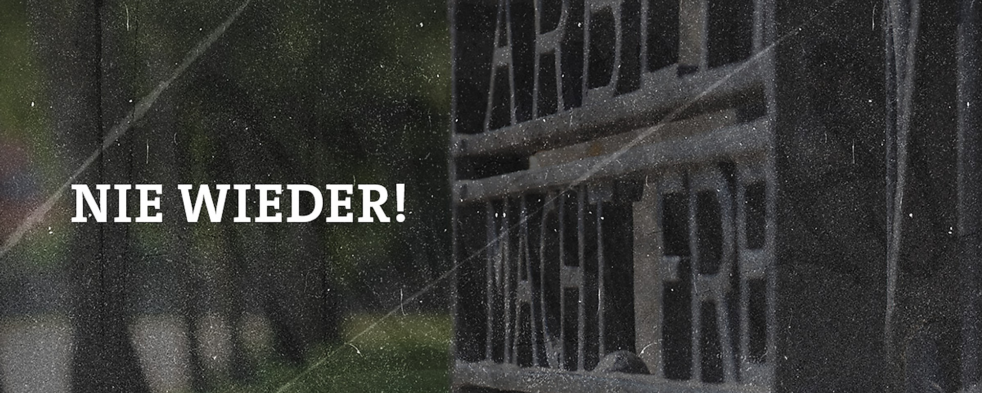 Das Eingangstor des Konzentrationslagers Dachau mit der Aufschrift Arbeit macht frei. Dazu der Schriftzug Nie wieder!