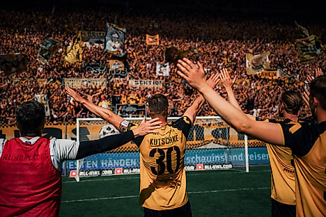 Stefan Kutschke mit zum Klatschen erhobenen Armen vor dem K-Block.