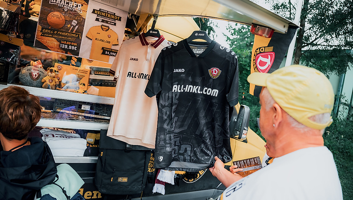 Ein Mann begutachtet die Dynamo-Auswärtstrikots der Saison 2025/26 vor einem Dynamo-Fanshop-Verkaufsstand.