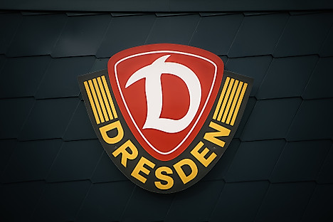 Das Wappen der SG Dynamo Dresden fotografiert auf dunkelgrauen Hintergrund