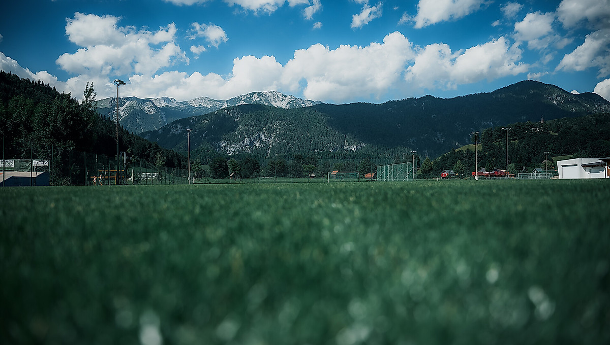 Ein Fußballplatz der am Fuß der Alpen liegt.