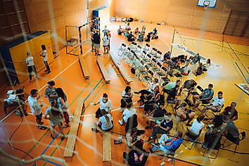 Eine Turnhalle in der sich viele Menschen versammelt haben