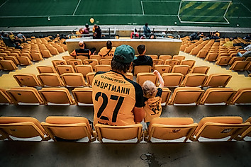 Ein Mann sitzt mit seinem Kind auf der Tribüne des Rudolf-Harbig-Stadions.
